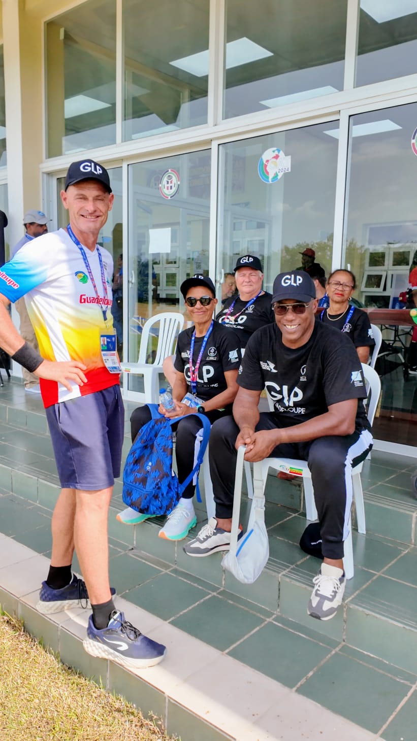 Un groupe en tenues sportives Guadeloupe, devant un bâtiment vitré.
